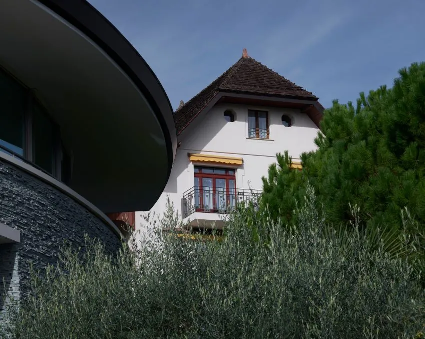 Clinique La Prairie in Montreux: historische Villa neben einem geschwungenen modernen Flügel, umrahmt von Olivenbäumen und Pinien